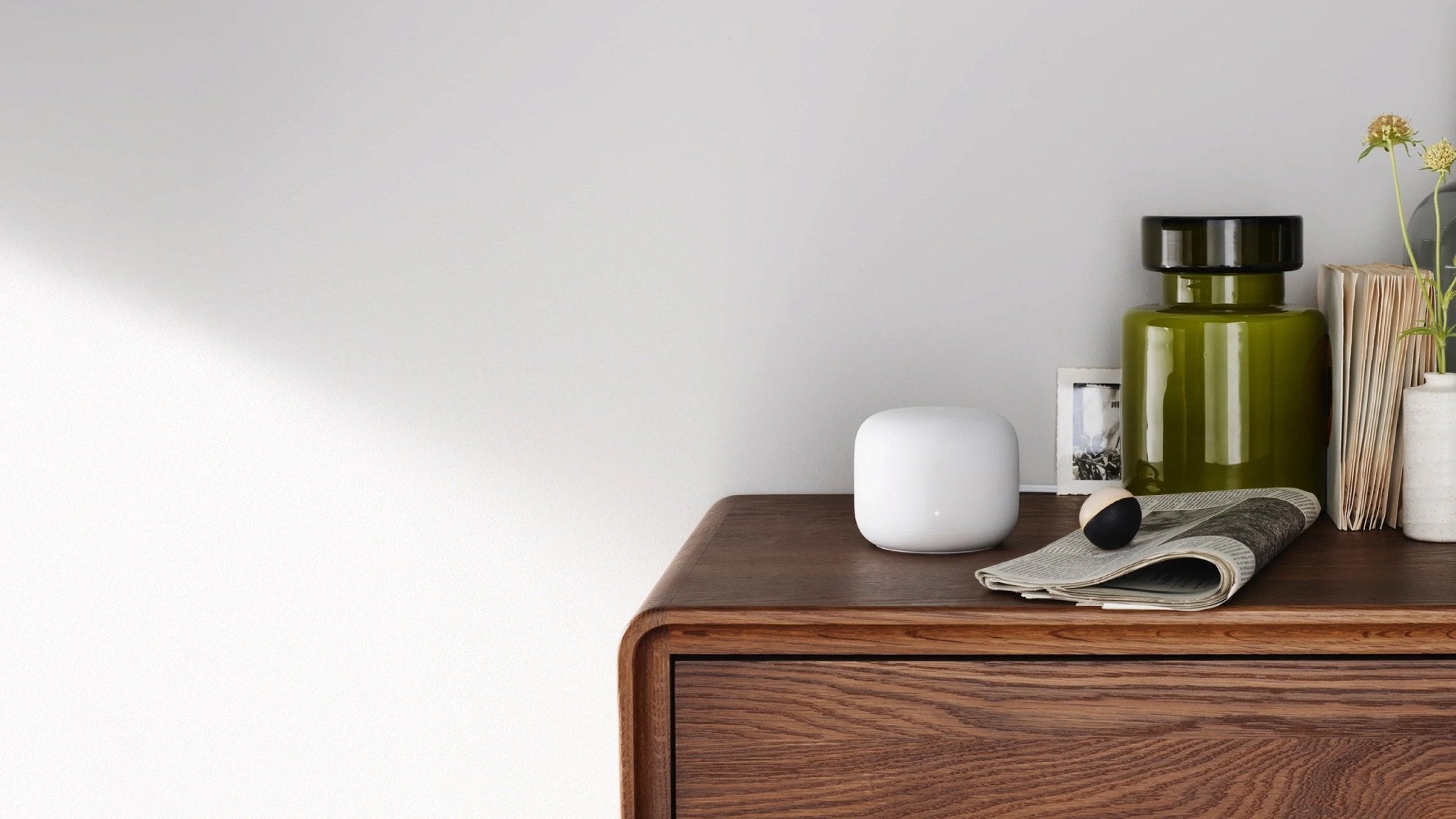 A Google Nest Wifi Snow displayed on a wood nightstand.
