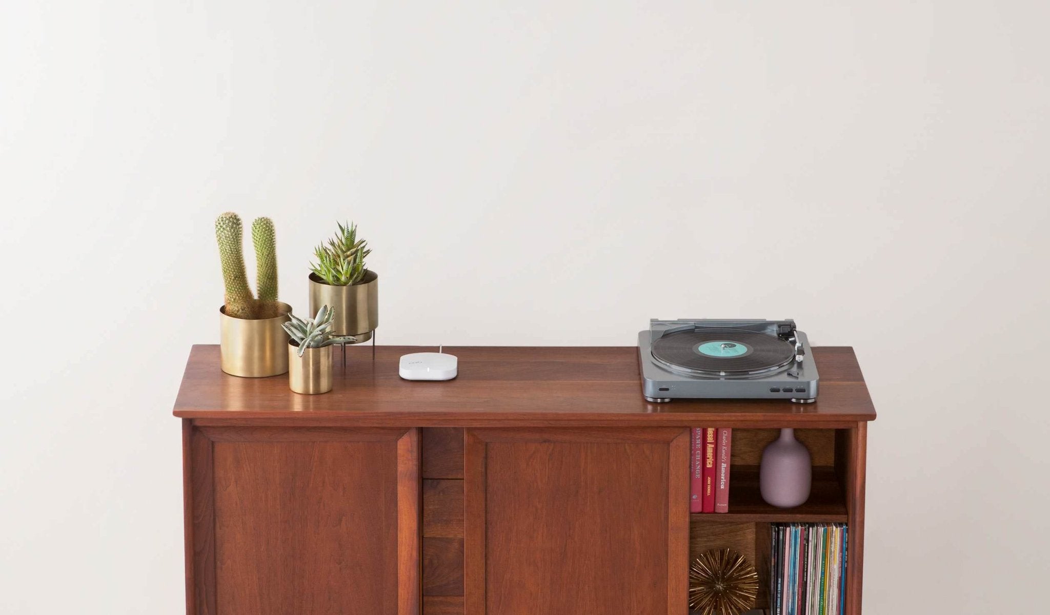 An Eero wireless mesh router installed on a wood media console.