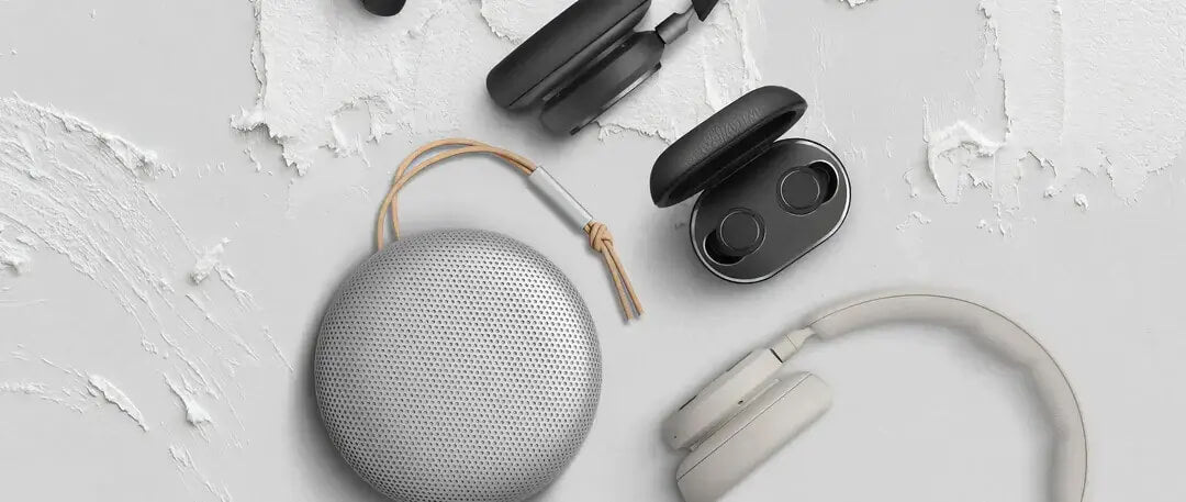A flat-lay image of earphones, a portable speaker, and headphones.